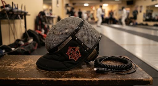 A fencing mask and academy gear resting on a bench
